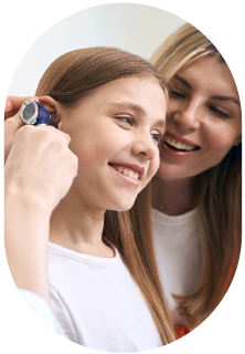 An audiologist looking in a young girl's ears during pediatric hearing tests