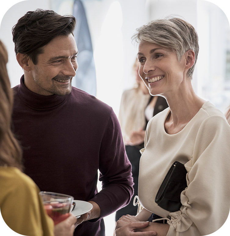 A woman and man smiling at a third person illustrating the importance of adult hearing tests to communicate effectively