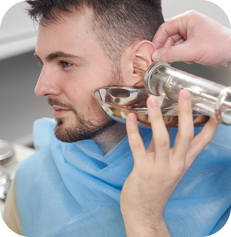 An audiologist performing earwax removal in Markham, Ontario on a man by flushing his wax out