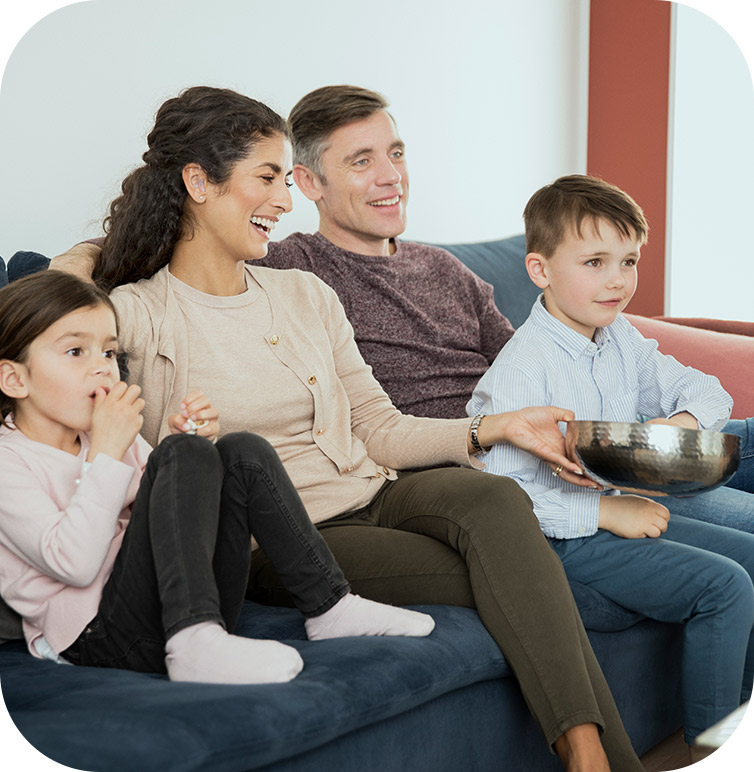 A family watching a movie and eating popcorn after the dad received Markham hearing aids