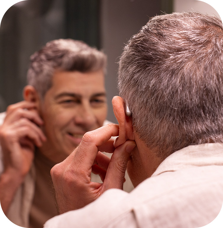 A man looking in mirror wearing the best hearing aids after using our hearing aid buying guide