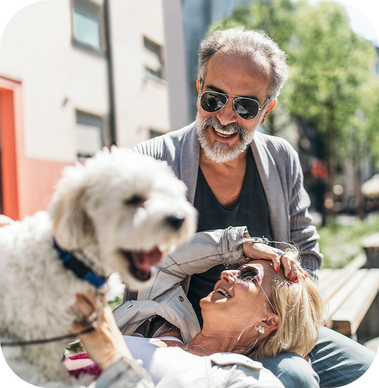 An older couple with a dog. The man has bone-anchored hearing aids or BAHA