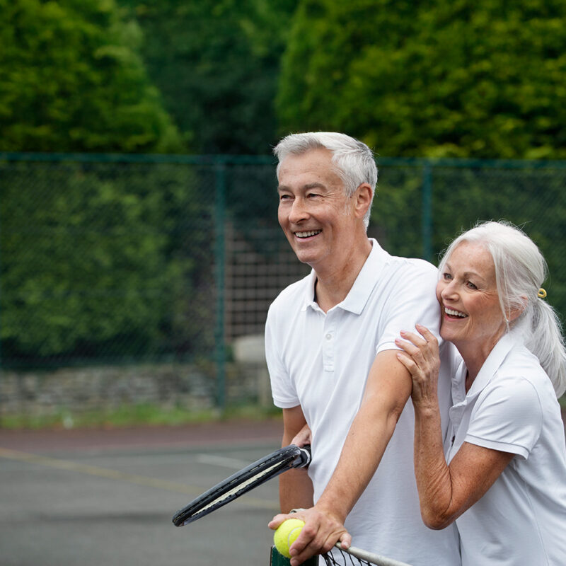 A couple with BAHA hearing aids playing tennis and laughing