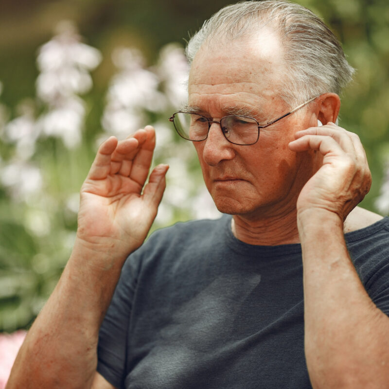 A man adjusting his hearing aid for a blog post on the different types of hearing loss