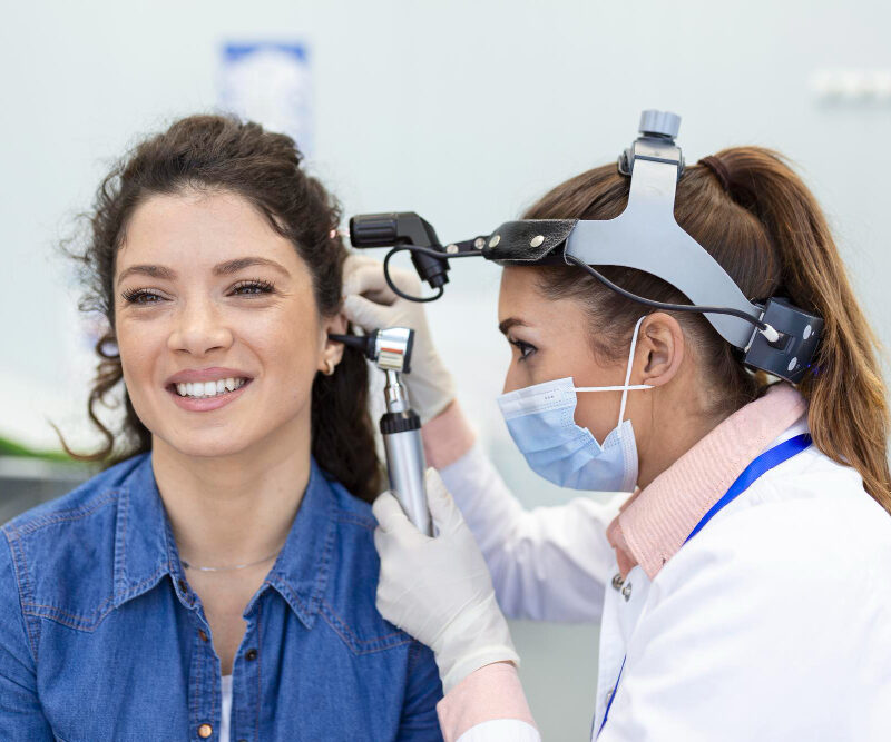 An audiologist inspecting a patient's ear to see if she's a candidate for ear wax removal